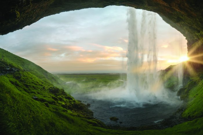 Fotobehang Uitzicht vanuit de grot op een natuurlijk landschap met een waterval