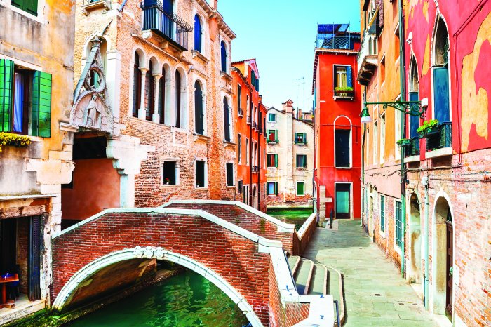 Fotobehang Een pittoresk kanaal met een brug omgeven door huurkazernes
