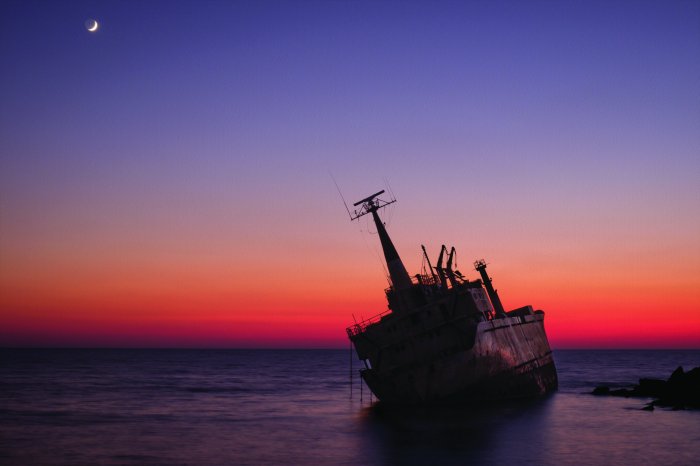 Fotobehang Een schipbreuk tegen de achtergrond van de ondergaande zon