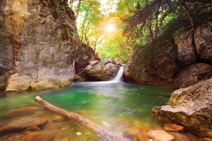 Fotobehang Berglandschap met een waterstroom die in de rivier stroomt