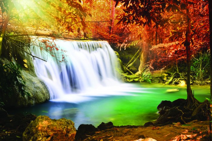 Fotobehang Landschap van zonnestralen over een waterval in de herfst