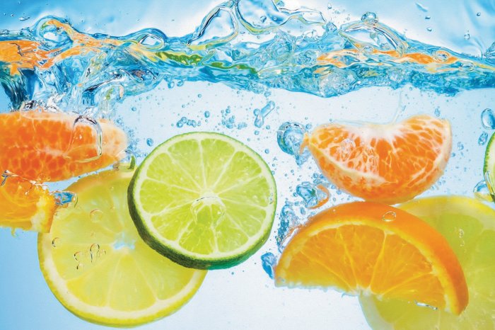 Fotobehang Citroenen en sinaasappelen vallen in het water