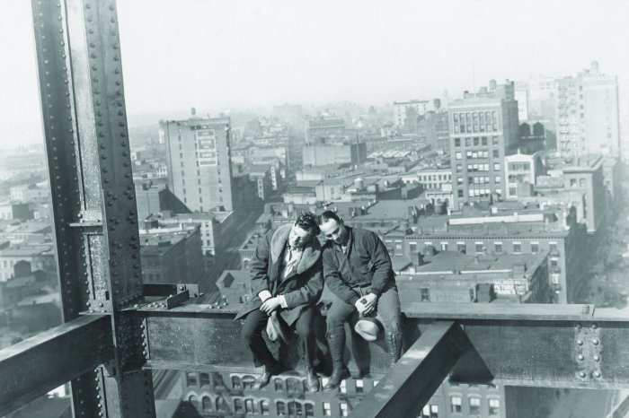 Fotobehang Mannen op een stalen frame in een stadsgezicht