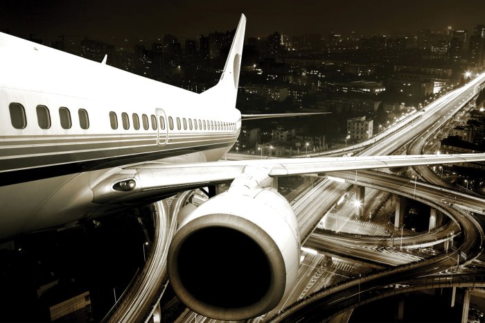 Fotobehang Een vliegtuig boven de stad &#39;s nachts