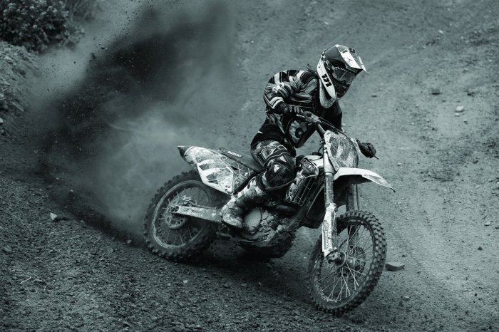 Fotobehang Een motorrijder met helm op een motorcrossbaan in zwart-wit