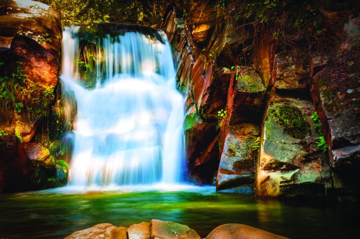 Fotobehang Rotsen en een waterval in het bos, omgeven door natuurlijk landschap