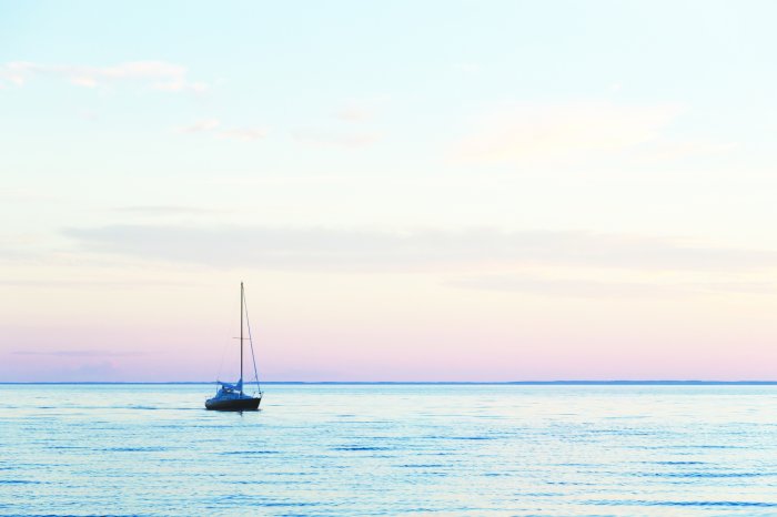 Fotobehang Een zeilboot op een kalme zee bij zonsondergang