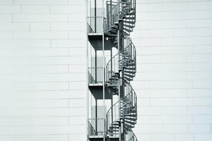 Fotobehang Stijlvolle wenteltrap tegen een lichte bakstenen muur