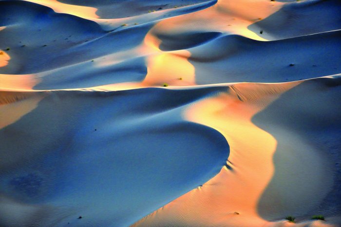 Fotobehang De zonnestralen vallen op het glooiende woestijnzand