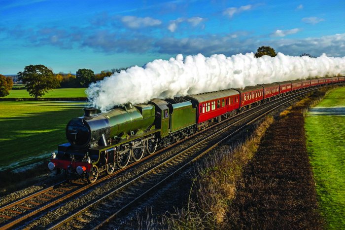 Fotobehang Een stoomlocomotief die door groene velden rijdt