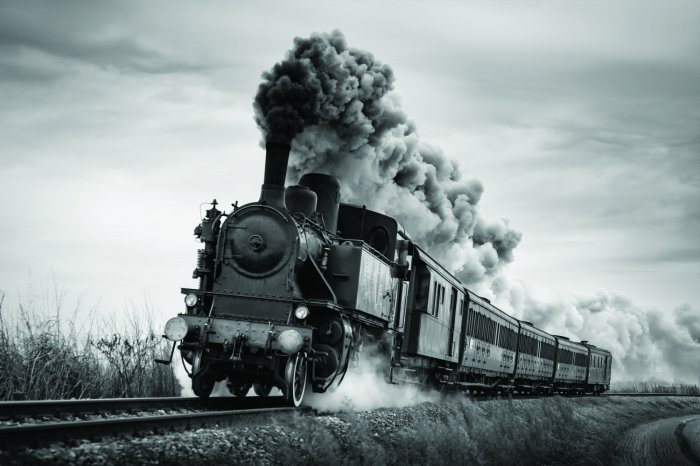 Fotobehang Een zwart-witfoto van een rijdende stoomlocomotief.