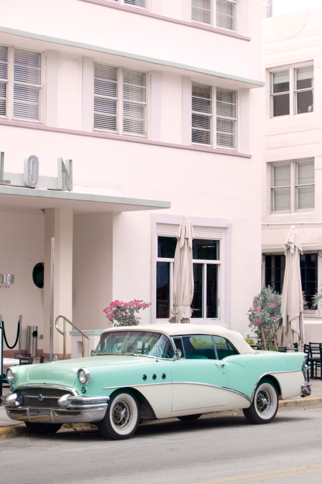 Canvas Een blauwe klassieke auto voor een roze hotel