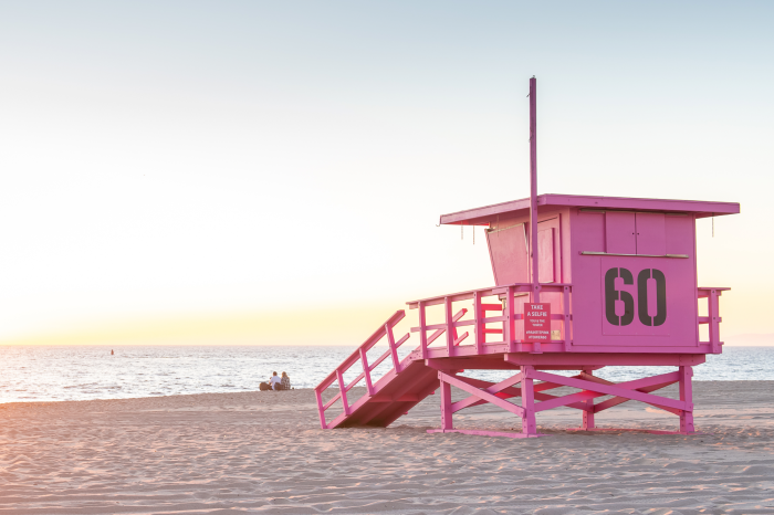 Canvas Een pastelkleurige strandwachtpost met uitzicht op de oceaan bij zonsopgang