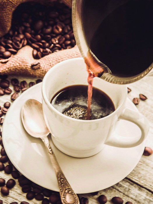 Canvas Een kopje gevuld met koffie met granen op de achtergrond