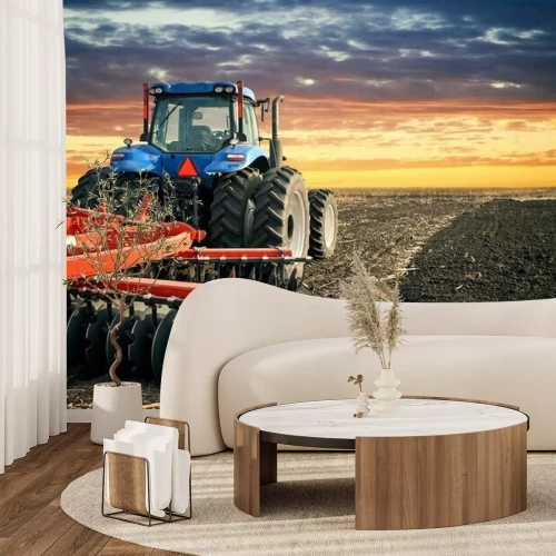 Fotobehang Tractor ploegend gebied op zonsondergangachtergrond