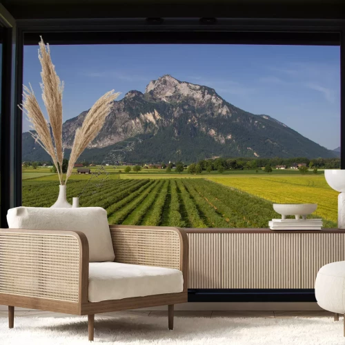 Fotobehang Uitzicht vanaf een open raam, van een berg, met een groen veld aan de voorkant