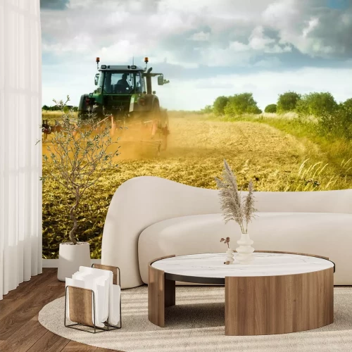 Fotobehang Tractor ploegt het veld