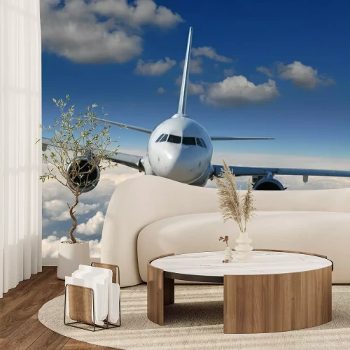 Fotobehang Een vliegtuig dat op een heldere dag boven de wolken vliegt