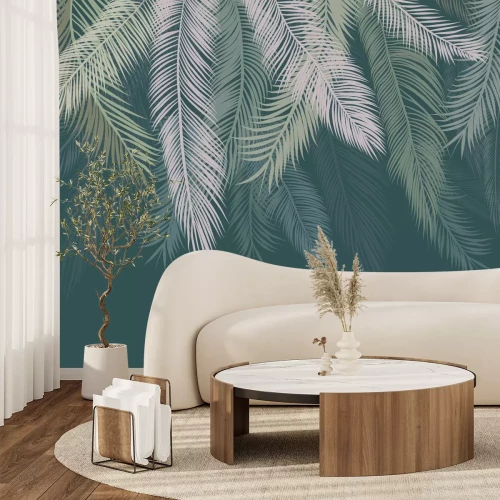 Fotobehang Palmbladeren hangen van bovenaf tegen een groene achtergrond