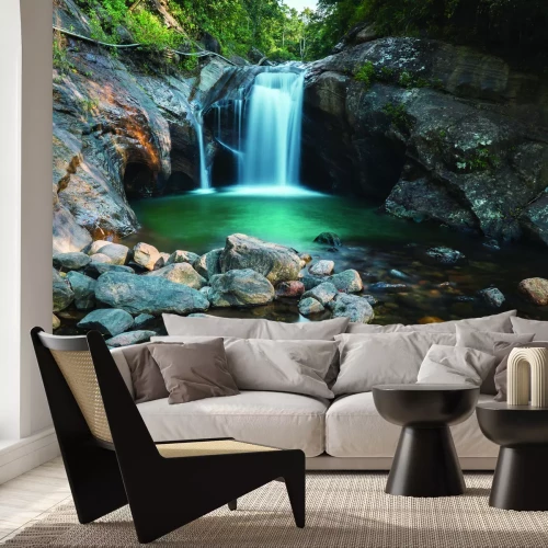 Fotobehang Een stroom van een waterval in het bos tegen een achtergrond van rotsen en stenen