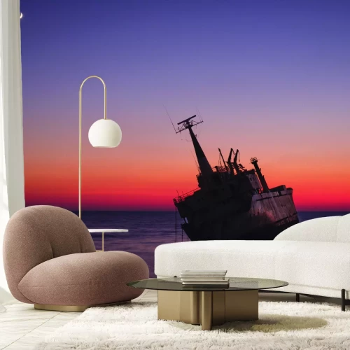 Fotobehang Een schipbreuk tegen de achtergrond van de ondergaande zon