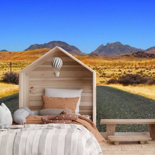 Fotobehang Een rechte betonnen weg die door een uitgestrekte woestijn snijdt