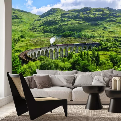 Fotobehang Een trein rijdt over een brug in een bergachtig landschap