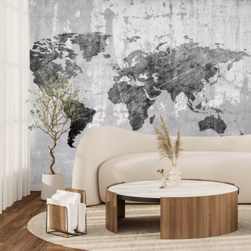 Fotobehang Een wereldkaart in grijstinten tegen een betonnen achtergrond