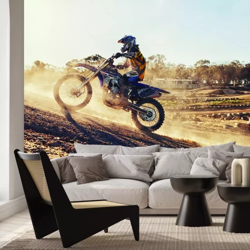Fotobehang Een crossmotorrijder rijdt bergopwaarts in het stof