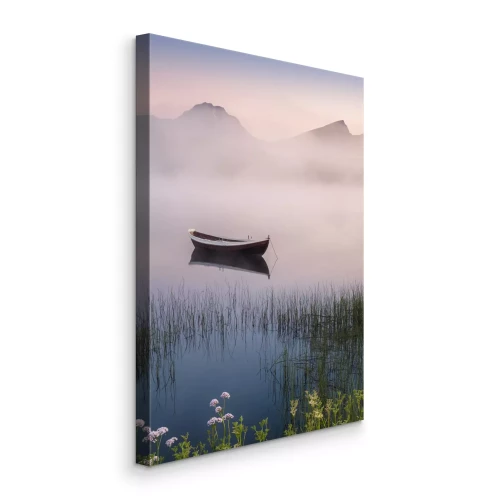 Canvas Een verlaten boot op een meer met bergen op de achtergrond in de mist