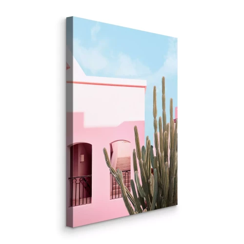 Canvas Een roze huis en een cactus tegen een blauwe lucht