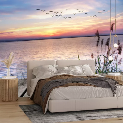 Fotobehang Uitzicht op zee in de warme kleuren van de zonsondergang