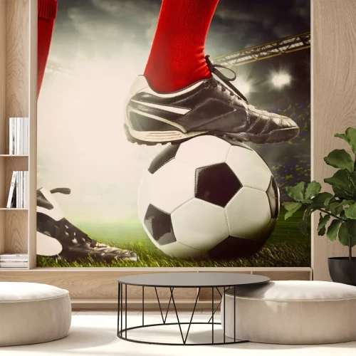 Fotobehang De benen van de voetballer op een bal