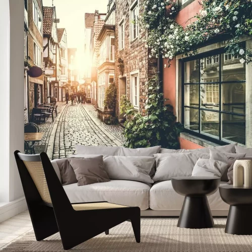 Fotobehang Een smalle straat met een zonsondergang op de achtergrond