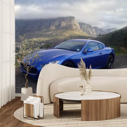 Fotobehang Een blauwe Maserati met een berglandschap op de achtergrond