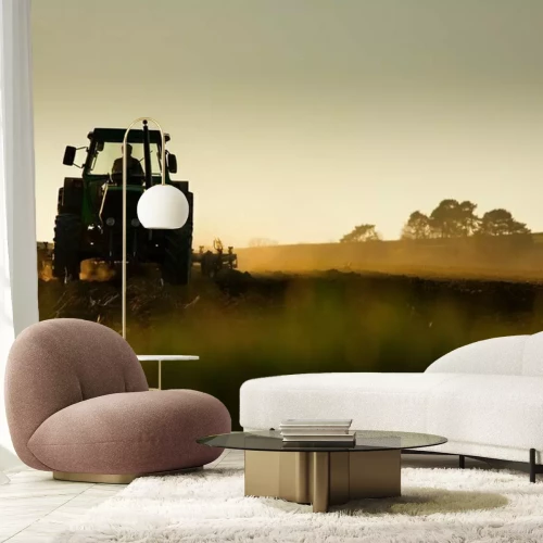 Fotobehang Tractor in een veld bij zonsondergang