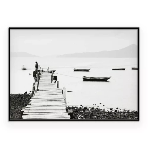 Poster Zwart-witbeeld van een man op een pier en boten op het water