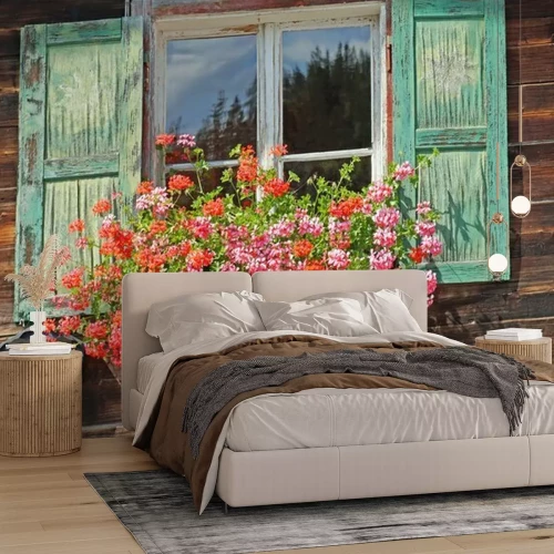 Fotobehang Een oud raam met turquoise luiken en bloemen op de vensterbank