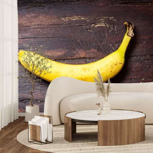 Sticker Een banaan op een donker houten oppervlak gelegd
