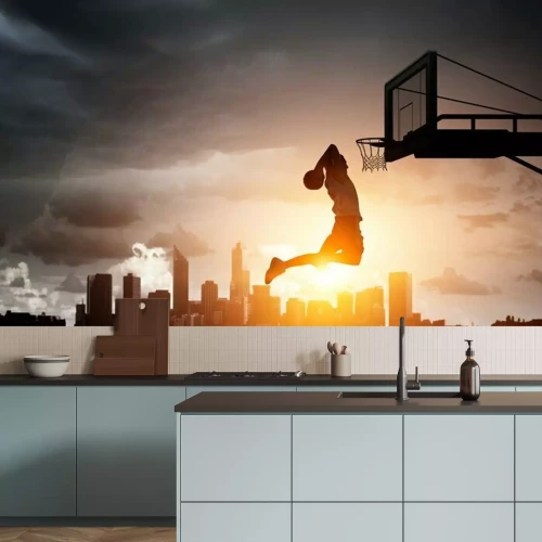 Fotobehang Een basketballer met een bal in de basket tegen de achtergrond van de zonsondergang