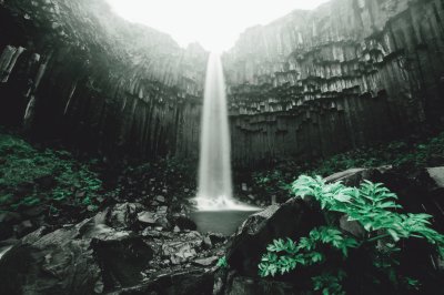 Fotobehang Waterval in een grot met groene planten