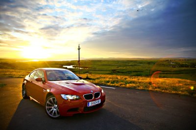 Fotobehang Bucharest, Romania - July 3, 2013: A BMW M3 car drives through a beautiful scenery, at sunset. The BMW M3 is a high-performance version of the BMW 3-Series, developed by BMW's motorsport division, BMW