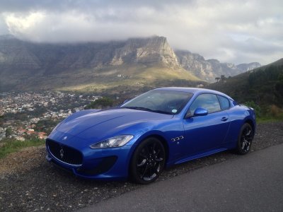 Fotobehang Een blauwe Maserati met een berglandschap op de achtergrond